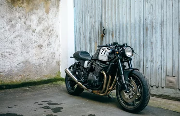 Foto auf Acrylglas Motorrad Glänzendes, maßgeschneidertes Motorrad, das vor dem Garagentor geparkt ist
