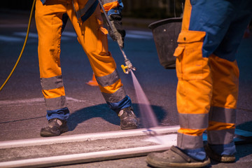 Traffic line painting. Workers are painting white street lines on pedestrian crossing
