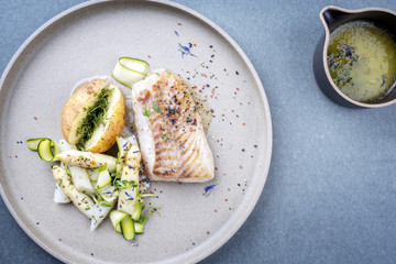 Modern style German fried cod fish filet with white asparagus tips and roast potatoes as top view...