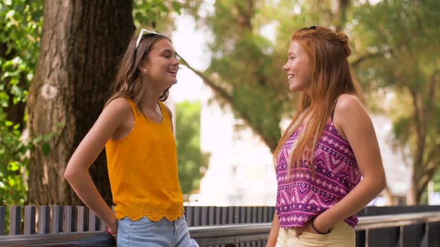 leisure and friendship concept - happy smiling teenage girls or friends talking in summer park