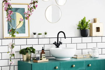 Close-up of a flower, graphic on the wall and wash basin on a turquoise cupboard. Real photo