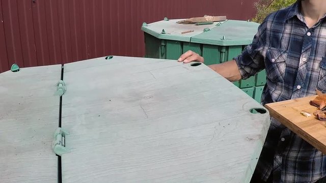 Farmer's hands throwing out kitchen waste to the garden compost heap for recycling and fertilizer. Top view, slow motion.