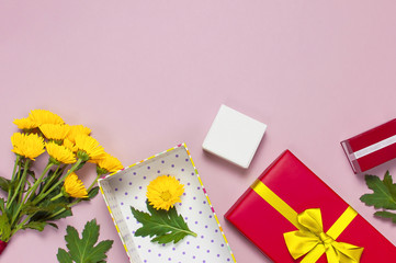 Obraz na płótnie Canvas Red gift box with gold ribbon and yellow chrysanthemums on pink background top view flat lay. Holiday concept, birthday gift, valentine day or anniversary. Congratulations background copy space.