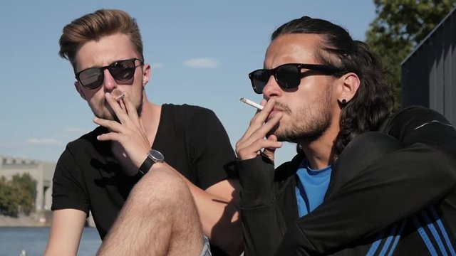 Two Boys Friends smoking Cigarettes on a City Quay - Hot Summer Day