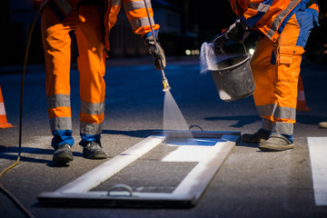 Traffic line painting. Workers are painting white street lines on pedestrian crossing
