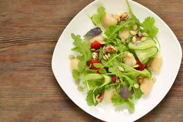 Mixed salad with white beans, greens, cucumbers and sweet peppers, top view, copy space