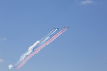 A group of professional military aviation pilots on military aircraft show tricks in the evening sky, leaving beautiful traces of clouds.