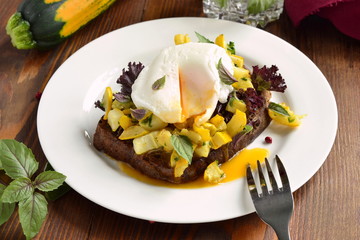 Healthy breakfast - toast with roasted yellow zucchini, pesto and poached egg