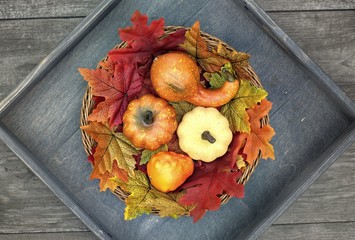 Seasons, background and texture concept-close up of a basket with colorful autumn leaves on a wooden background.