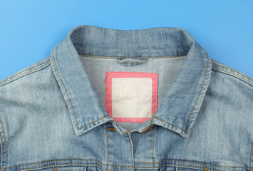 Clothes, shoes and accessories - top view fragment blue jeans jacket empty label blue background