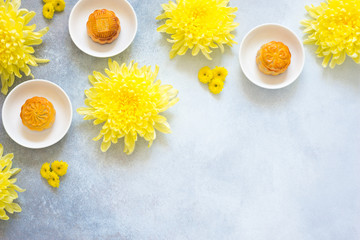 Mooncakes, chrysanthemum flowers on grey background with copy space. Chinese mid-autumn festival food.