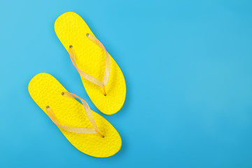 Clothes, shoes and accessories - top view yellow pair flip flops blue background