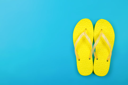 Clothes, shoes and accessories - top view yellow pair flip-flops blue background