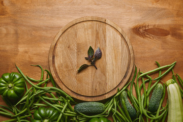 Organic raw green vegetables with round board on wooden table
