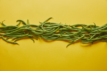 Obraz premium Green beans in a row on yellow background