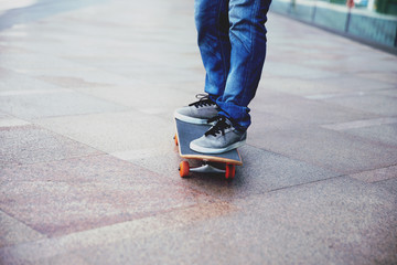 Skateboarder legs riding skateboard on city street