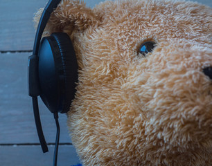 a teddy bear in the headphones on wooden background