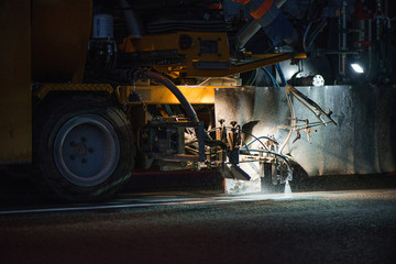 Thermoplastic spray marking machine during road construction works at night. Traffic line painting...