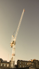 A white metallic crane extending into a grey sky.