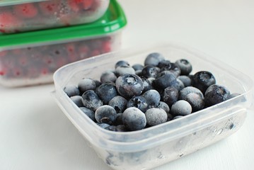 Frozen summer berries in plastic containers. Frozen blueberries.