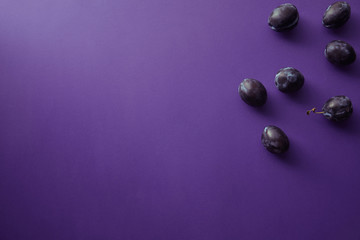 top view of ripe plums on violet surface