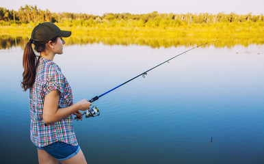 Cute woman is fishing with rod on lake