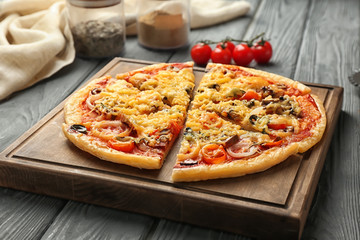 Board with tasty sliced pizza on wooden table
