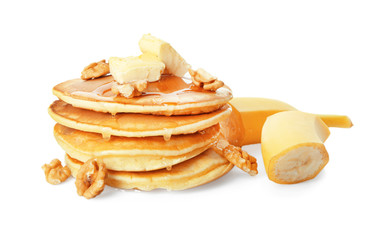 Tasty pancakes with sliced banana, butter and walnuts on white background