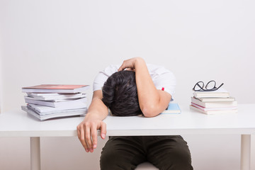 Man tired of studying. Young man sleeping on the table with book opened, weary & tired of reading (studying)
