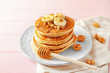 Tasty pancakes with walnuts and sliced banana on table
