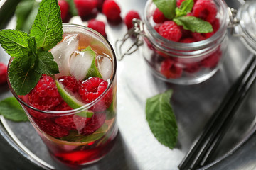 Glass of fresh raspberry mojito on metal plate