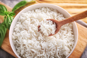 Bowl and spoon with boiled white rice on table