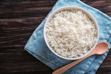 Bowl with boiled white rice on wooden table