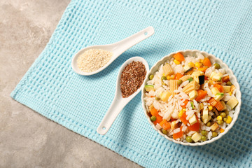 Bowl with tasty boiled rice and vegetables on table