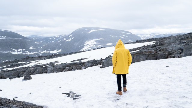 person with yellow jacket walking over snow