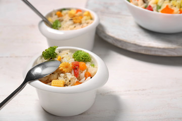 Bowl of tasty rice with vegetables on white table