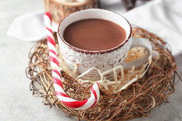 Obraz na płótnie Canvas Cup of tasty cocoa in decorative nest on light background