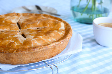 Cooling rack with delicious apple pie on table, closeup
