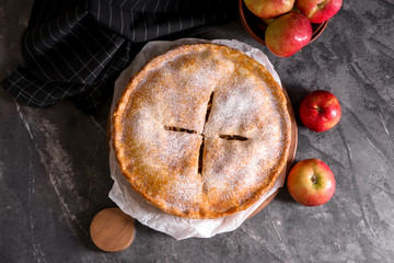 Board with delicious apple pie on dark table