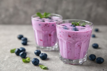 Glasses of tasty blueberry smoothie on light table