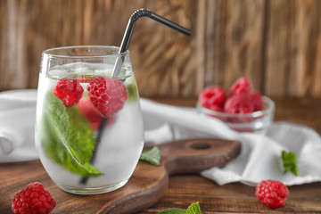 Glass of fresh raspberry mojito on board