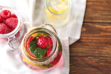 Glass jar of fresh raspberry mojito on wooden table