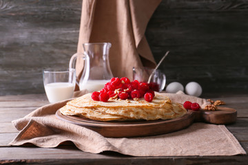 Delicious thin pancakes with berries and nuts on wooden table