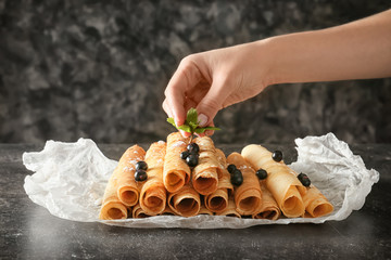 Woman decorating thin pancakes with mint