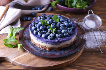 Plate with delicious blueberry cheesecake on wooden table