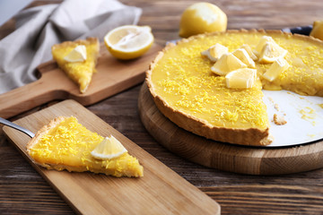 Tasty cut lemon pie on wooden table