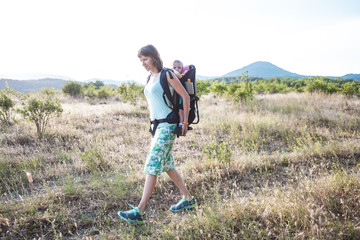 A woman is carrying a backpack with her baby.