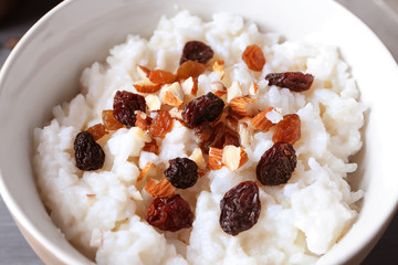 Bowl with delicious rice pudding, nuts and raisins, closeup