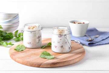 Glass jars with delicious rice pudding and nuts on board