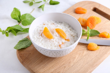 Bowl with delicious rice pudding and dried apricot on board